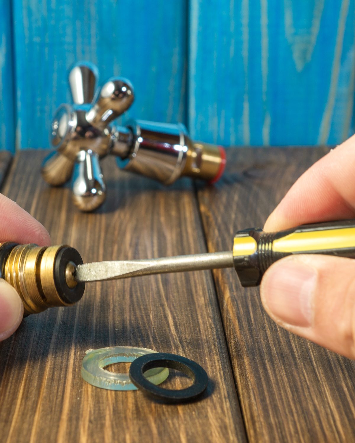 Tap valve held open with a screwdriver, its washers laid out on the bench